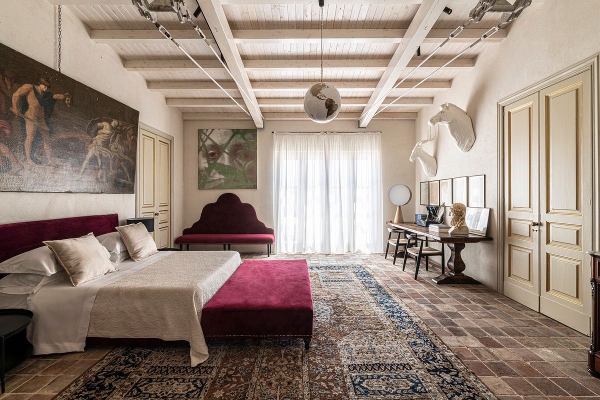 Camera con soffitto a travi, dipinto antico e letto con panca bordeaux