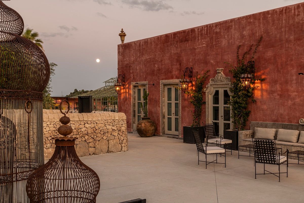 Terrazza al tramonto con lanterne a gabbia e muro rosso